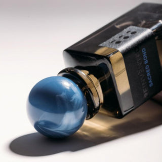 Botella sofisticada de Sacred Bond Reinvented, con un acabado negro profundo y un tapón azul iridiscente.